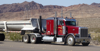 Semi rolling down the road in front of mountains